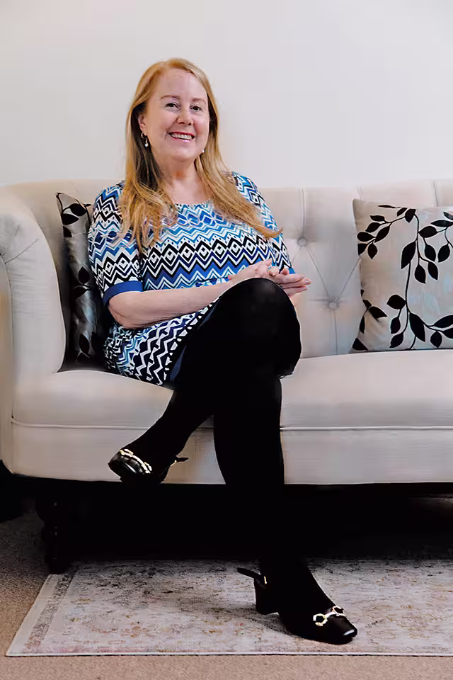 Jennifer L Zauner LCSWR Sitting on gray couch in the middle office