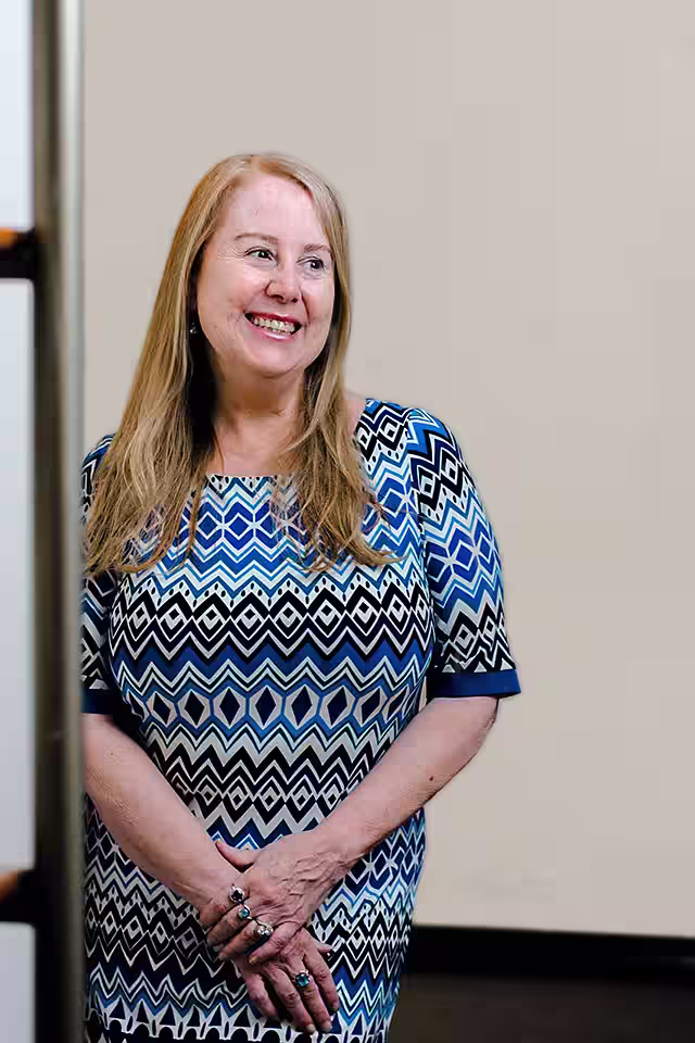 Jennifer L Zauner LCSWR Clinical Director of Sirona Therapy leaning in hallway looking to her right and smiling