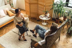 Therapist office with natural colors and lighting. Therapist in chair facing and talking to client.